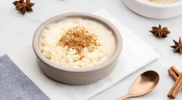 Un tazón de arroz con leche cremoso, espolvoreado con canela. ¿Quién inventó el arroz con leche? Un misterio delicioso.