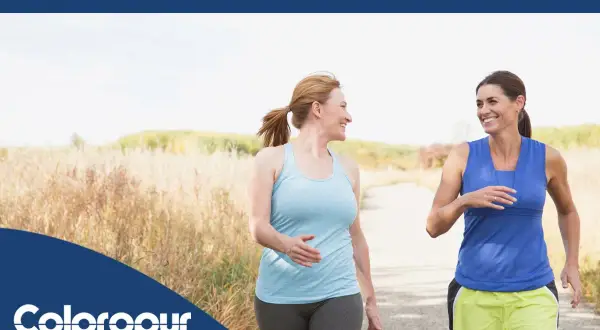 Due donne sorridono mentre camminano su un sentiero, godendosi i benefici della camminata.