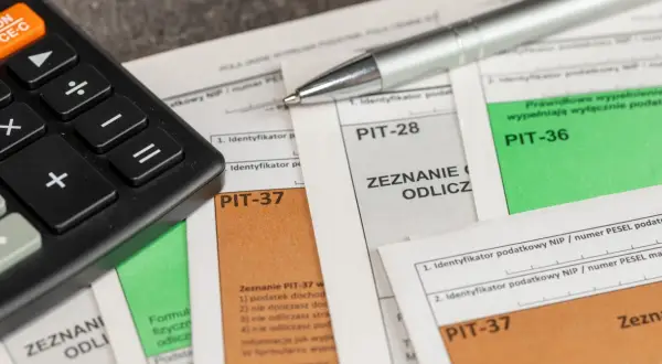 Kalkulator i długopis na dokumentach PIT. Przygotowanie do rozliczenia ulgi rehabilitacyjnej na samochód.
