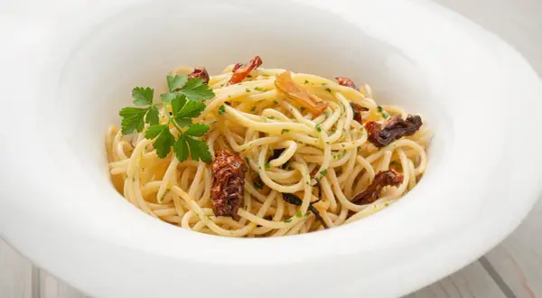 Espaguetis al ajillo, un plato sencillo pero delicioso, con pasta dorada, trozos de ajo crujiente y perejil fresco.
