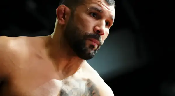 Rodolfo Vieira, en MMA-fighter med intensiv blick och tatueringar på bröstet, förbereder sig för strid.