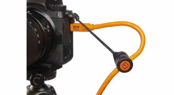 En orange Tether Tools-kabel ansluten till en Nikon-kamera, redo för säker överföring av bilder.
