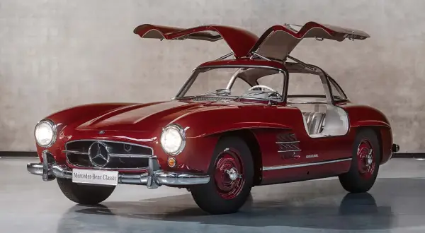 Czerwony Mercedes 300 SL z otwieranymi do góry drzwiami, prezentujący swoje klasyczne piękno.