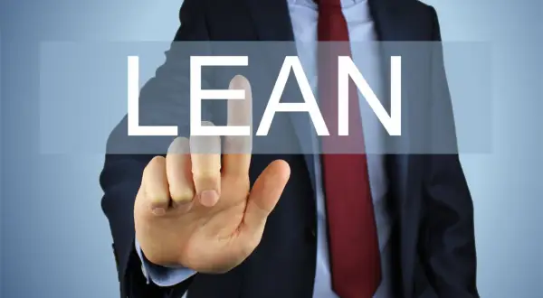 Biznesmen w garniturze dotyka ekranu z napisem "LEAN".