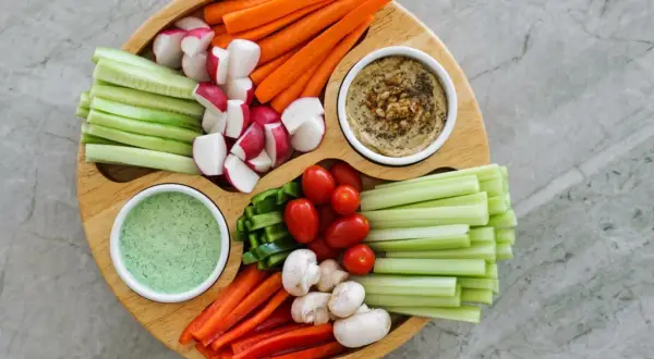 Bunter Gemüseteller mit Hummus und Dip – perfekt für einen 1000 kcal am Tag Essensplan. Karotten, Gurken, Radieschen, Paprika, Tomaten, Sellerie und Pilze.