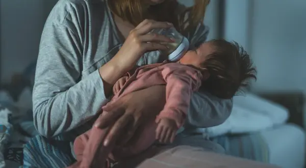 Mama karmi butelką noworodka, dbając o jego potrzeby. Mały brzuszek mieści niewielką ilość mleka, co odzwierciedla pojemność żołądka noworodka.