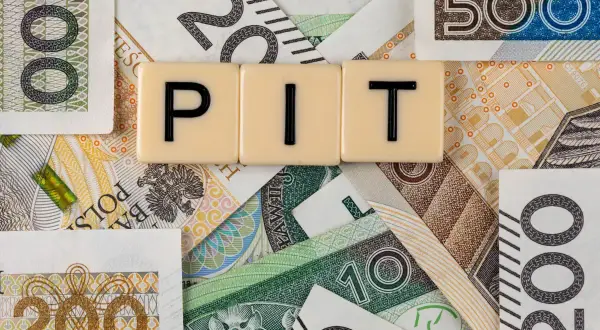 Litery "PIT" na tle polskich banknotów o nominałach 10, 20, 100, 200 i 500 zł.