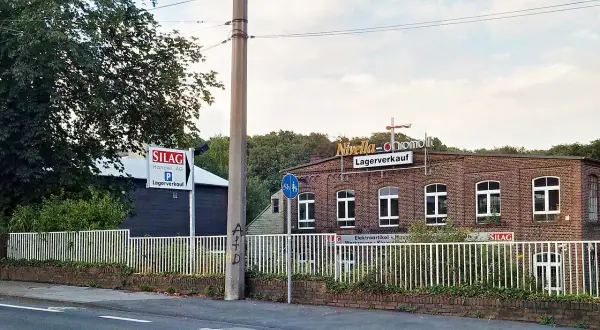 Ziegelgebäude mit Schildern "Nivella-chromolit Lagerverkauf" und "SILAG Handel AG Lagerverkauf" in Piepersberg, Solingen.