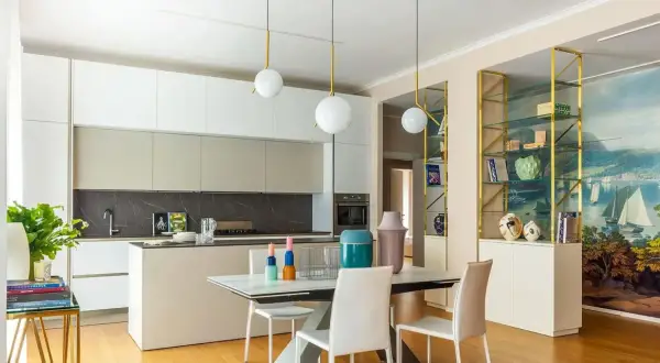 Cucina moderna con isola e zona pranzo. Parete con libreria dorata e affresco marino, un'ispirazione per idee pareti soggiorno moderne.
