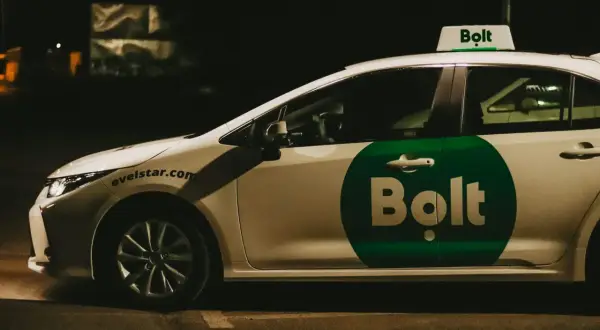 Biały samochód z zielonym logo Bolt na drzwiach i na dachu. To usługa transportowa, co to jest Bolt?