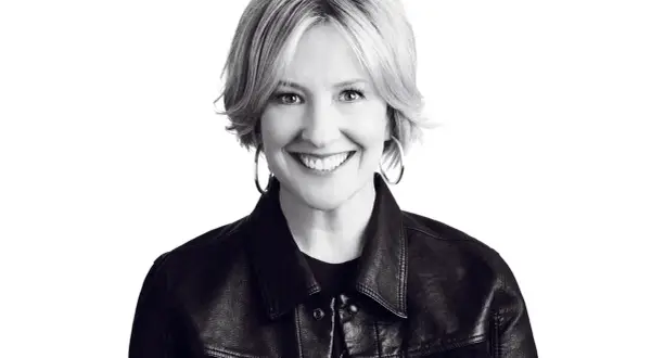 Uśmiechnięta Brené Brown w skórzanej kurtce, uosobienie odwagi i autentyczności.
