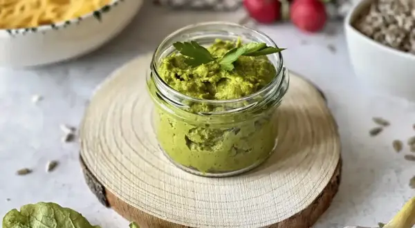 Słoiczek domowego pesto z bazylii, gotowy do podania z makaronem. Obok czosnek i słonecznik.