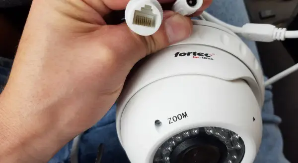 Dłoń trzyma białą kamerę IP z logo "fortec for vision". Widać złącze RJ45 i zasilania. Dowiedz się, jak podłączyć kamerę bez rejestratora.