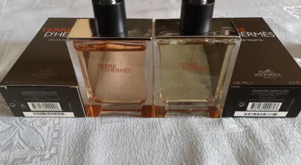 Dwa flakony Terre d'Hermès EDT, każdy 100 ml, stoją na białym obrusie.