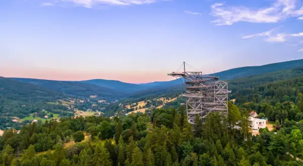 Metalowa konstrukcja sky walk wznosi się na znaczną wysokość nad zalesionymi wzgórzami, oferując zapierające dech w piersiach widoki.