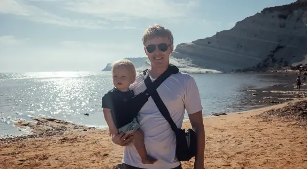 Ojciec z niemowlakiem na plaży, idealne miejsce, gdzie na wakacje z niemowlakiem. Słońce, morze i białe klify tworzą piękne tło.