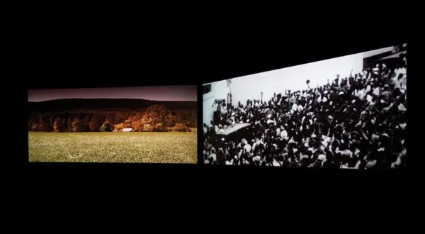 John Akomfrah art: a split screen showing a pastoral landscape with a small building and a dense crowd of people cheering.