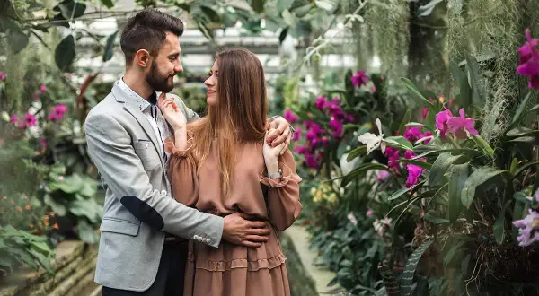 Zakochana para w otoczeniu kwitnących orchidei. Zastanawiasz się, ile kosztuje sesja u fotografa?