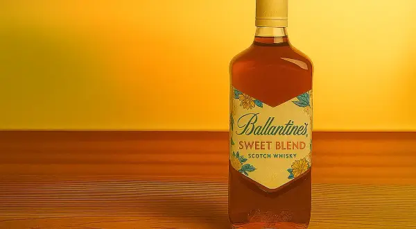 Butelka Ballantine's Sweet Blend na drewnianym blacie. Idealna do drinków, np. z colą lub jako baza do koktajli. Z czym pić Ballantines Brasil?