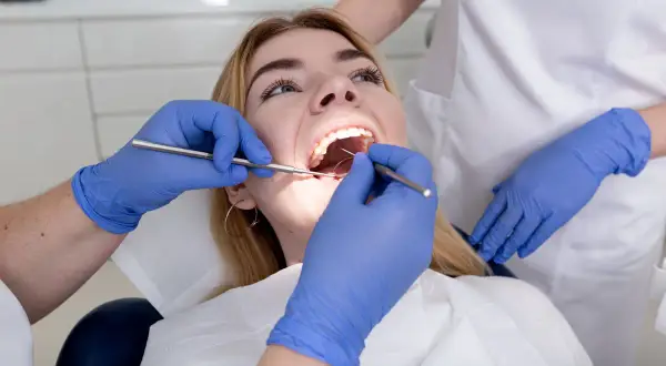 Dentysta bada zęby pacjentki. Czy plomba może wypaść? Specjalista ocenia stan uzębienia.