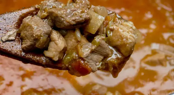 Gulasz wieprzowy na drewnianej łyżce. Kiedy solić mięso wieprzowe na gulasz? Najlepiej na początku, by wydobyć smak.