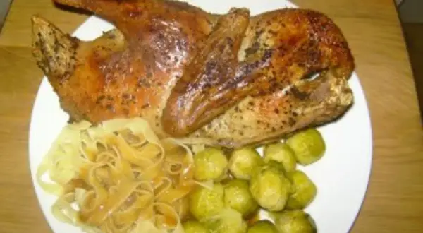 Halbe Ente braten, goldbraun und knusprig, serviert mit Bandnudeln und Rosenkohl. Ein Festmahl!