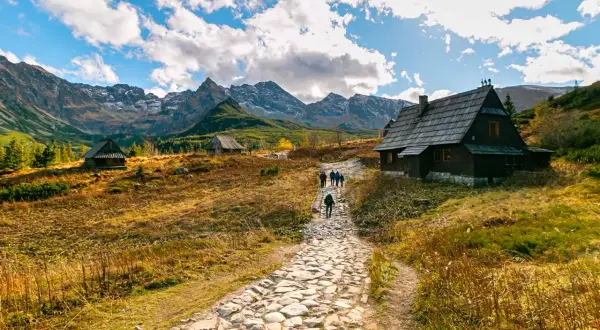 Kamienna ścieżka prowadzi do górskich chat. W oddali majestatyczne Tatry. To piękne zakopane atrakcje.