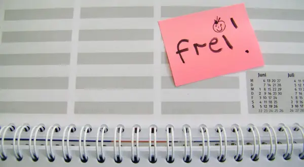 Ein rosa Zettel mit "frei!" und einem lachenden Smiley auf einem Kalenderblatt. Der Zettel könnte für den Freizeitausgleich nach Krankheit stehen.