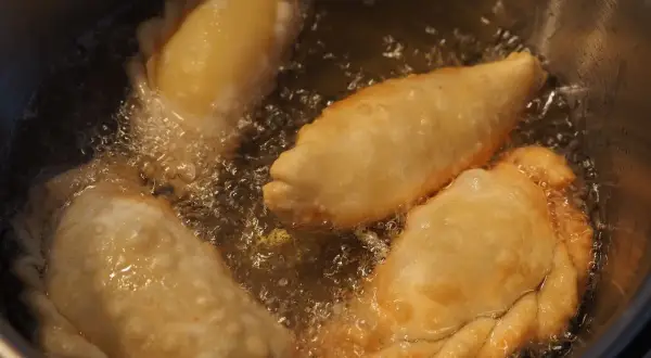 Empanadas de queso dorándose en aceite burbujeante. El aroma tentador llena la cocina.