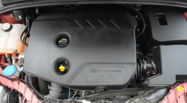 Silnik Duratorq TDCI w Fordzie Focus MK3 1.6. Widoczna czarna osłona silnika z logo.