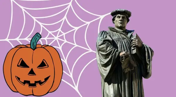 Reformationstag statt Halloween: Martin Luther Statue neben Kürbis und Spinnennetz.