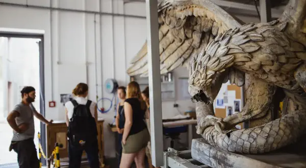 Studierende im Restaurationsstudium betrachten eine detailreiche Skulptur eines geflügelten Wesens.