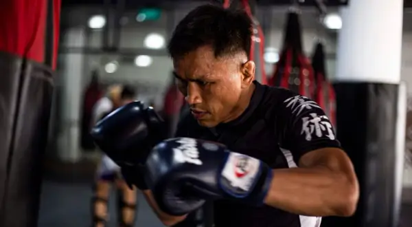 A boxer, sweat beading on his brow, trains intensely. This image shows why is boxing so tiring: constant movement, powerful strikes, and unwavering focus.