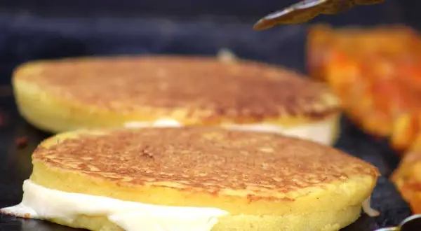 Arepas de choclo doradas y rellenas de queso derretido, listas para ser disfrutadas.