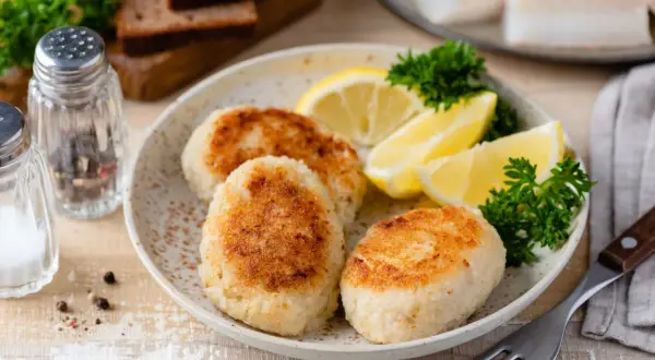 Filetti di merluzzo surgelati trasformati in gustose polpette, servite con spicchi di limone e prezzemolo. Perfette per ricette veloci e saporite.
