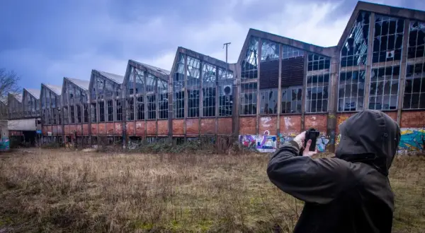 Exploration urbex à Angoulême : une silhouette capture l'architecture délabrée d'une usine abandonnée, ornée de graffitis.