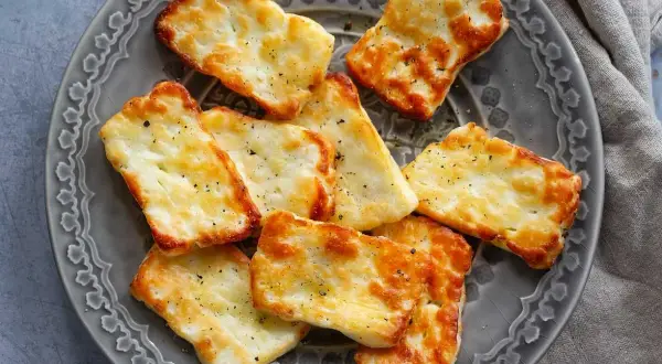 Gylla halloumi i airfryer, gyllene och krispiga bitar på en grå tallrik, kryddade med peppar.