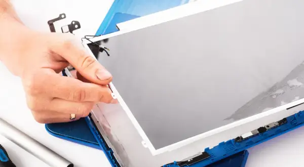Dłoń trzyma nową matrycę do laptopa, gotową do montażu. Wymiana matrycy w laptopie to precyzyjna praca.
