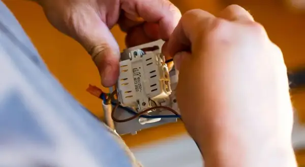 Ręce montują mechanizm włącznika. Zastanawiasz się, ile za punkt elektryczny?