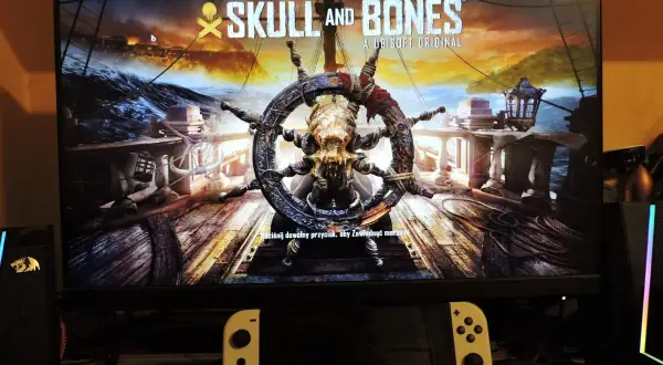 Logo gry "Skull and Bones" z kołem sterowym ozdobionym czaszką i kośćmi.