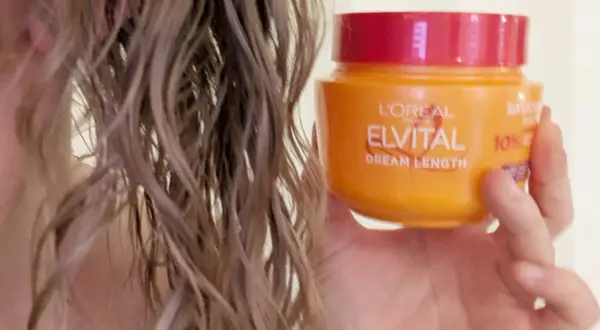 En hand håller en burk L'Oréal Elvital Dream Length hårinpackning bredvid vått hår. Hur ofta hårinpackning behövs beror på hårets skick.