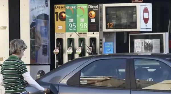 Persona repostando gasolina 95 o 98. El surtidor muestra los precios de los combustibles.