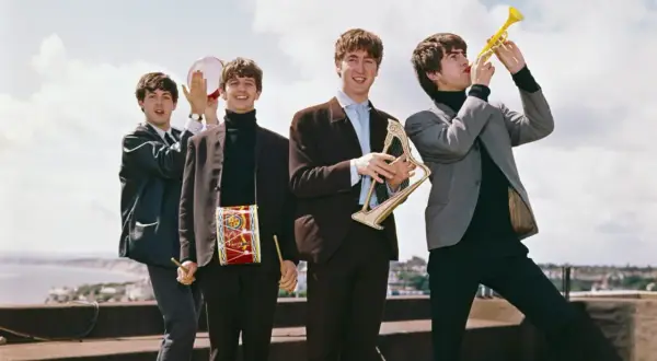 The Beatles grają na instrumentach, tworząc piosenki. George gra na trąbce, John na harfie, Paul na tamburynie, a Ringo ma bębenek na szyi.