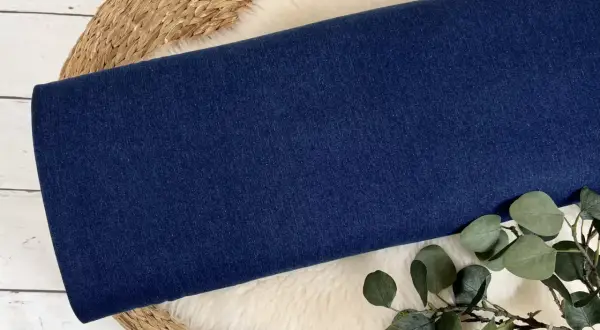 Dunkelblauer Denim-Stoff, aus dem Jeans gemacht sind, liegt auf einem Schaffell.