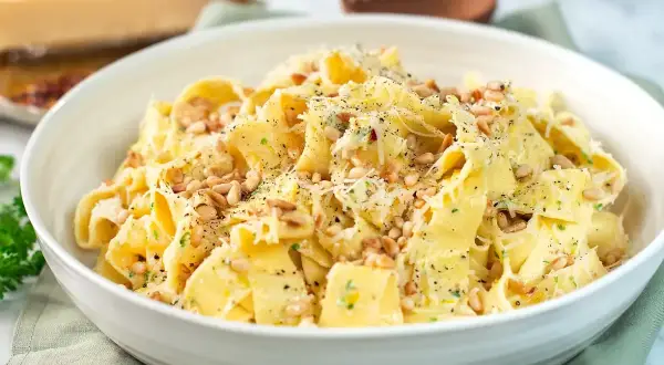 En skål med krämig citronpasta, toppad med pinjenötter och riven parmesan. En härlig rätt som passar perfekt för en snabb middag.