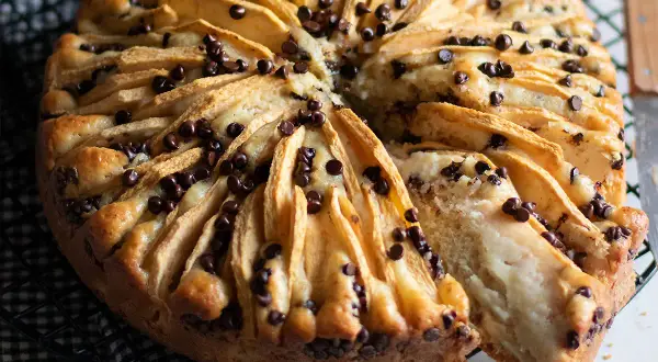 Delizioso dolce mele e cioccolato, con fette di mela disposte a raggiera e gocce di cioccolato fondente che si sciolgono nell'impasto soffice.