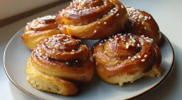 Fem gyllene kanelbullar med pärlsocker på en blågrå tallrik. Perfekt för att grädda bullar varmluft eller inte.