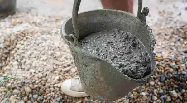 Secchio pieno di cemento fresco, pronto per essere utilizzato. Imparare come fare il cemento è fondamentale per ogni progetto di costruzione.