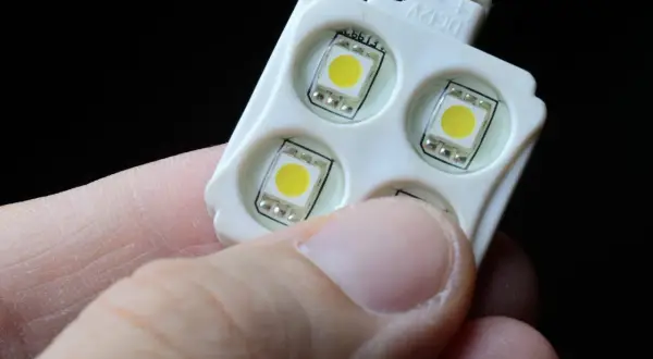 Moduł z czterema diodami LED, trzymany w dłoni, gotowy do podłączenia do włącznika światła.