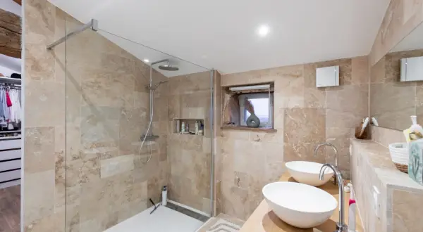 Salle de bain moderne avec douche à l'italienne et double vasque, une belle rénovation faience salle de bain en pierre naturelle.